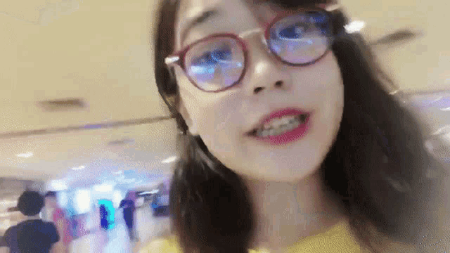 a woman wearing glasses and a yellow shirt smiles