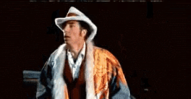 a man in a cowboy hat is standing next to a woman in a suit with the words toma esto written in white letters