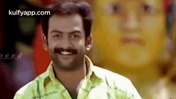 a man with a mustache is smiling with a woman 's face in the background .