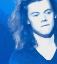 a close up of a man 's face with long hair against a blue background
