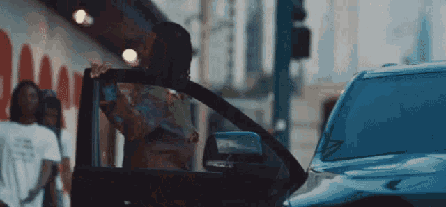 a woman is getting out of a car in front of a wall that says ' damn '
