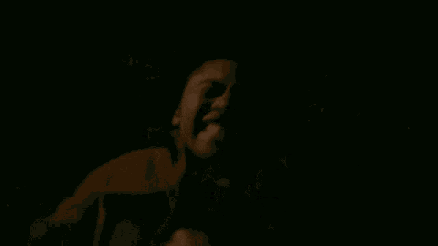 a close up of a man 's face in the dark with his mouth open