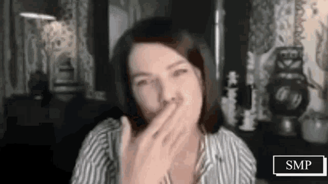 a woman is covering her mouth with her hand in a video call .