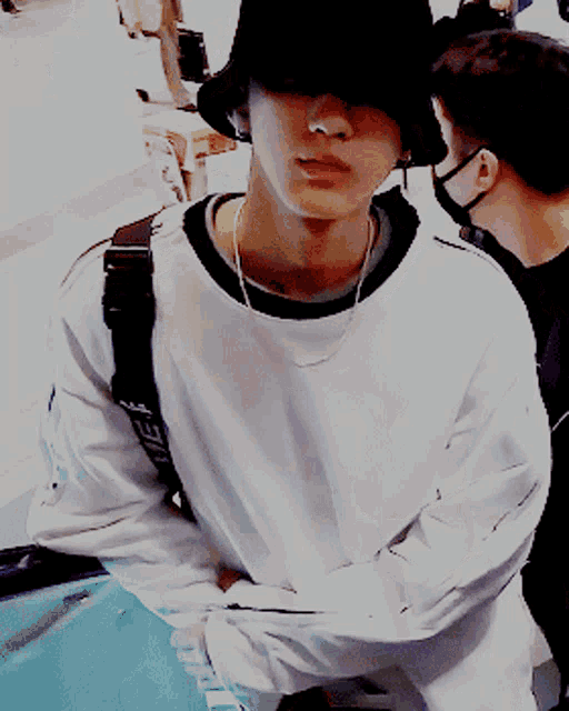 a young man wearing a black hat and a white sweater with the word supreme on it