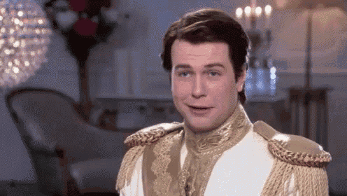 a man in a white and gold costume is standing in a living room and smiling .