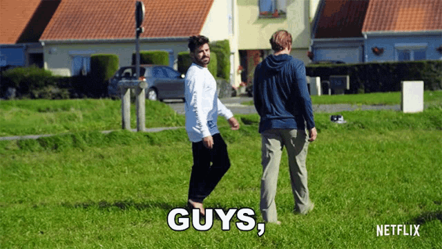 two men standing in a grassy field with the words " guys " on the bottom right