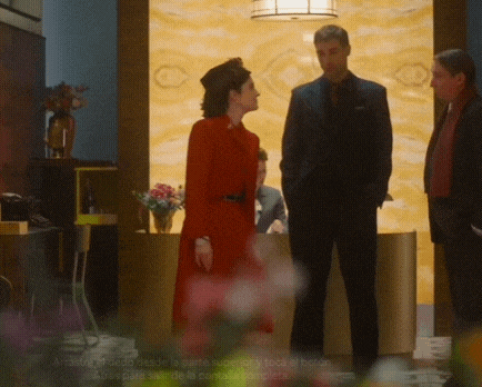 a woman in a red dress is standing in front of two men in suits .