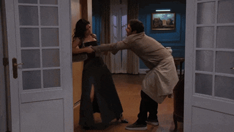 a man and woman are fighting in a room with a picture on the wall