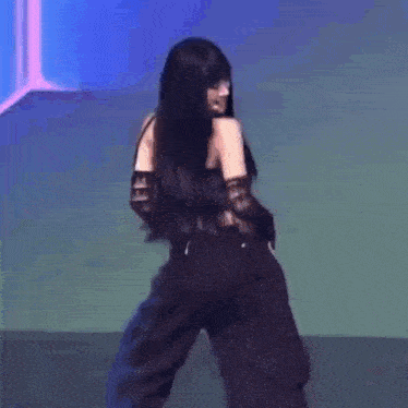 a woman is dancing on a stage wearing black pants and gloves .