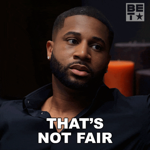 a man with a beard says " that 's not fair " in white letters
