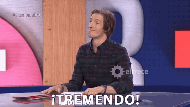 a man in a plaid shirt sits at a table with the words itremendo written on the bottom