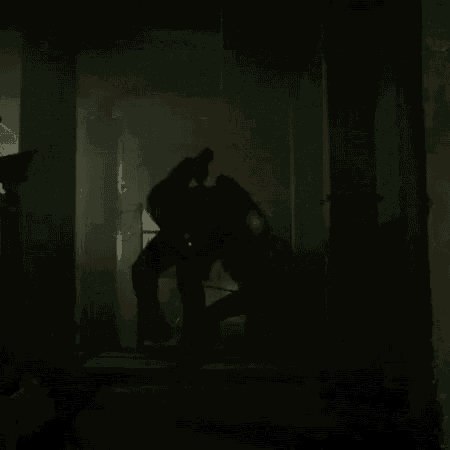 a couple of people are fighting in a dark room in a dark room .
