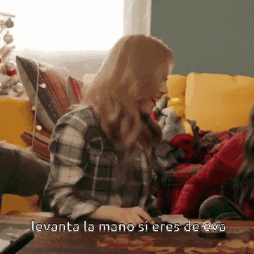 a woman in a plaid shirt sits at a table with the words levanta la mano si eres de eva written below her