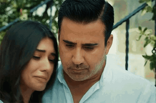 a man and a woman are sitting next to each other and the woman is crying