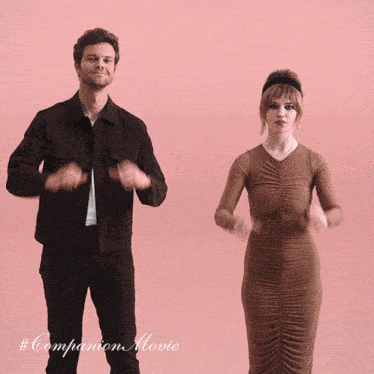 a man and a woman are clapping their hands in front of a pink background