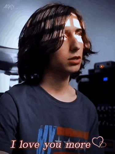 a young man with long hair is wearing a t-shirt that says " i love you more "