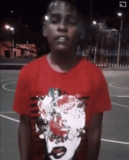 a young boy wearing a red t-shirt with a woman 's face on it