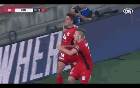two soccer players are celebrating a goal in front of an ad for fox sports