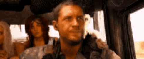 a man is sitting in the back seat of a car with two women behind him .