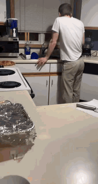 a man in a white shirt standing in a kitchen