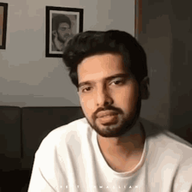 a man with a beard is wearing a white t-shirt with the word malik on it .