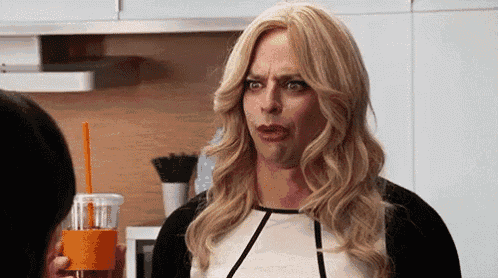 a man in a wig is holding a cup of coffee with a straw and making a funny face .