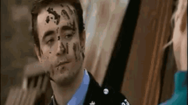 a man with chocolate on his face is standing next to a man .