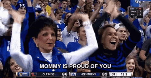 a crowd of people watching a basketball game with the words mommy is proud of you on the screen