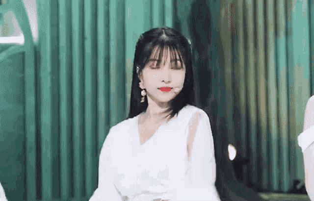 a woman in a white dress is standing in front of a green wall .