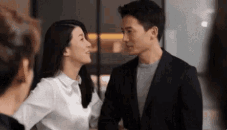 a man and a woman are standing next to each other and looking at each other in a room .