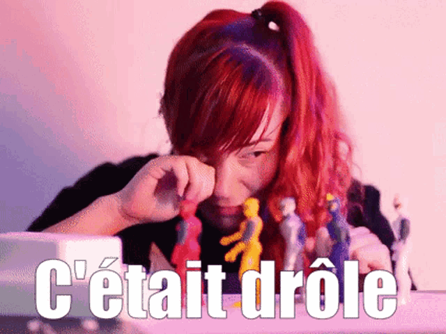 a woman with red hair is sitting at a table with the words c'était drole above her