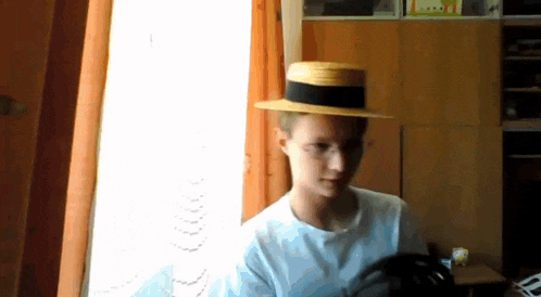 a young man wearing a straw hat and glasses looks at the camera