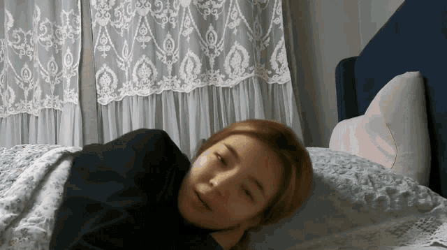 a woman laying on a bed with a heart shaped pillow