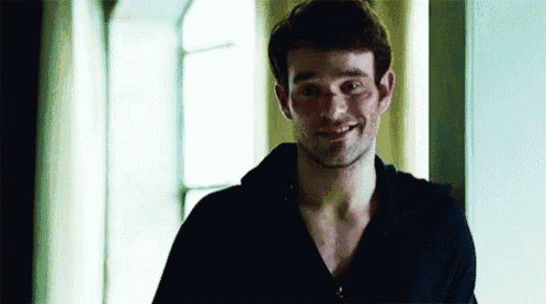 a man without a shirt is smiling and looking at the camera .