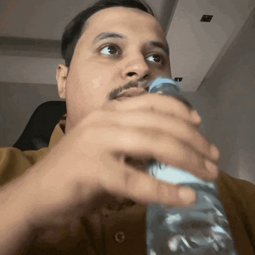 a man drinking water from a plastic bottle