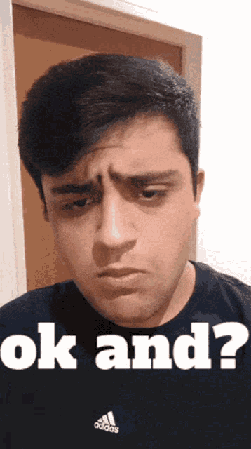 a man wearing an adidas shirt is making a face