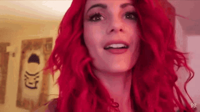 a woman with red hair is wearing a wig and smiling .