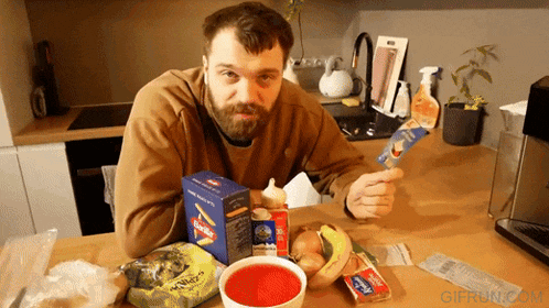 a man is sitting at a table with a box of chips and a bowl of sauce
