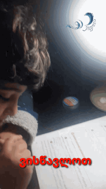 a person sitting at a desk with a foreign language on the bottom