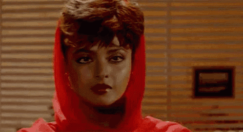 a woman wearing sunglasses and a red sweater is talking on a phone .
