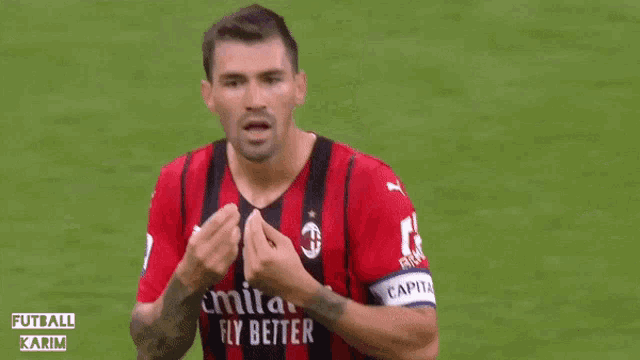 a soccer player wearing a red and black jersey that says emirates fly better