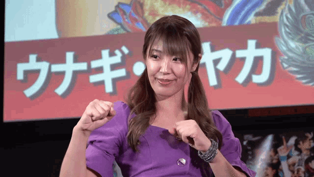 a woman in a purple dress stands in front of a screen with chinese characters