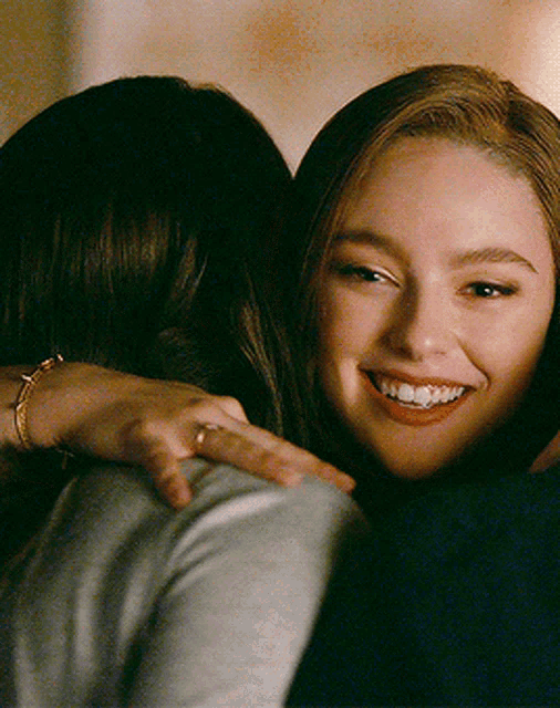 a woman is hugging another woman and smiling at the camera