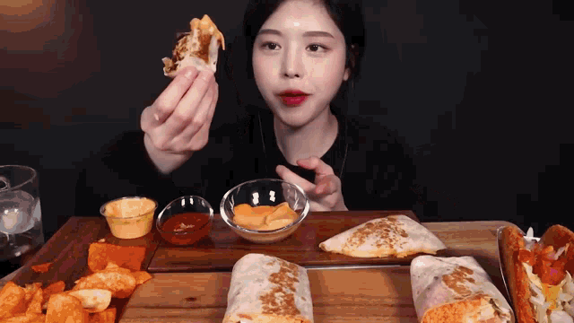 a woman is sitting at a table eating a tortilla wrap
