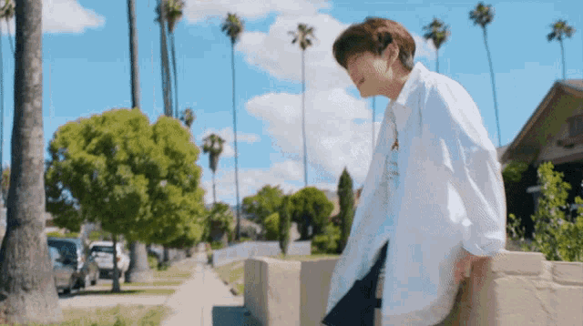a man in a white shirt is leaning against a stone wall