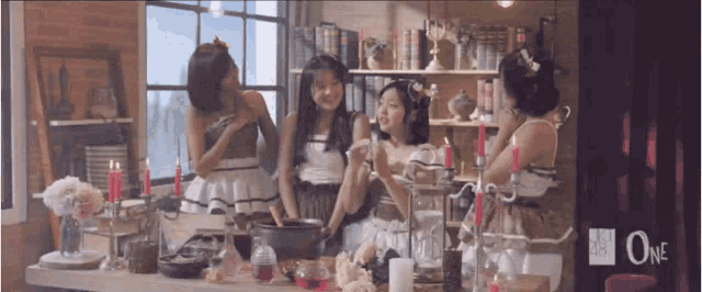 a group of girls are sitting around a table with candles and a sign that says one