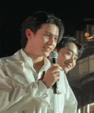 two young men are standing next to each other and one is holding a microphone