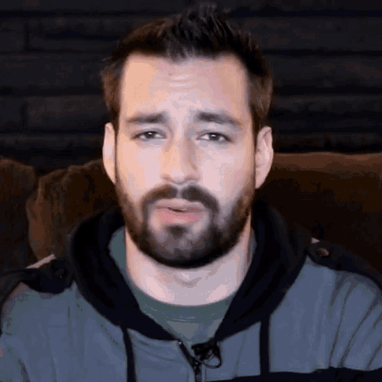 a man with a beard is sitting on a couch making a funny face