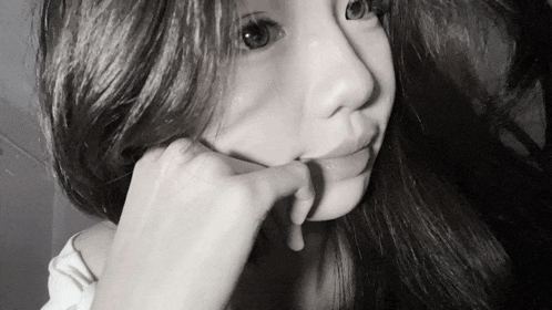 a black and white photo of a woman with her hand on her face