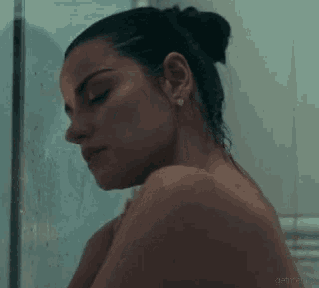 a woman is taking a shower in a bathroom and looking out the window .